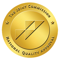 Gold circular badge displaying "The Joint Commission National Quality Approval" with geometric design in the center.